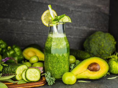 Healthy green smoothie in a glass bottle on dark stone background. Vegetarian food.