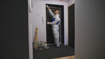 Worker in overalls, takes measurements of the doorway, he was a professional builder.