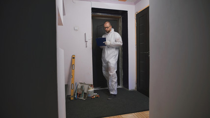 Worker in overalls, takes measurements of the doorway, he was a professional builder.