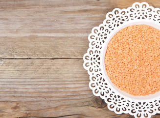 Red lentils on white plate with wooden background