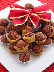 Chocolate truffles decorated with ribbon in a white plate. Verti