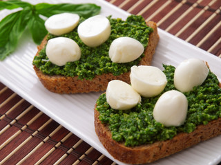 Two Italian bruschetta sandwiches with basil pesto and baby mozz