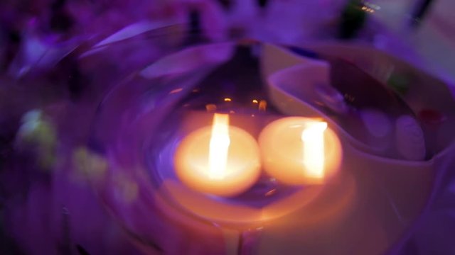 candles floating in a glass vase in the evening on a violet background lighting