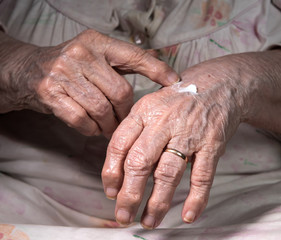 Fototapeta premium Old woman applying hand cream