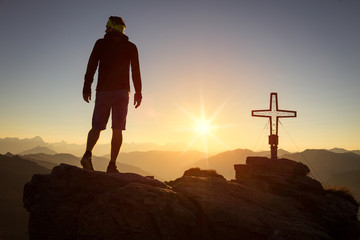 Man standing on a mountain summit at sunrise