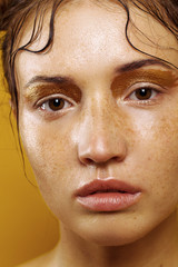 Portrait of a beautiful girl on a yellow background with the effect of wet skin