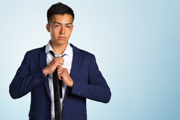 Confident young man adjusting his necktie