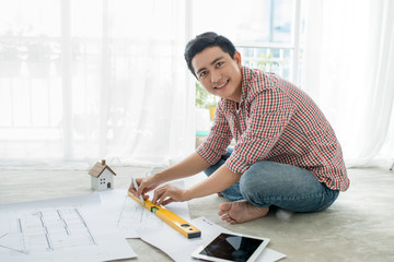 Young handsome male asian architect working at home on the floor