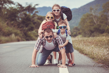 Father and children walking on the road at the day time.