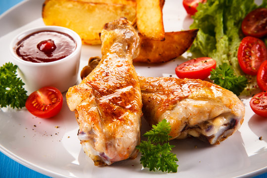 Grilled chicken legs with chips and vegetables