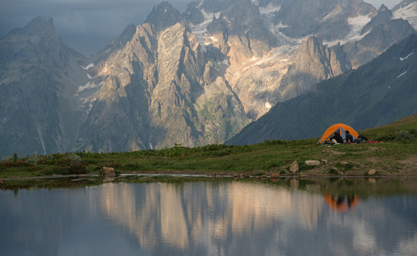 Orange camp  and tourists near mountain lake