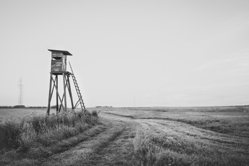 Wooden Hunting high tower on the meadow. Hunters lookout tower.