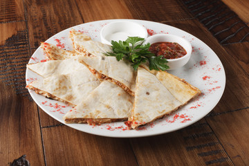 quesadilla with beef and chicken on brown wood table. quesadilla and sauce.