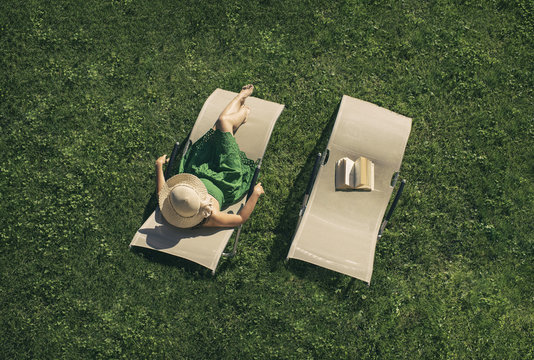 woman in the green dress lying on a sunbed with book