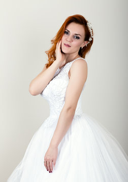 red-haired bride in a wedding dress, bright unusual appearance. Beautiful hairstyle and professional make-up