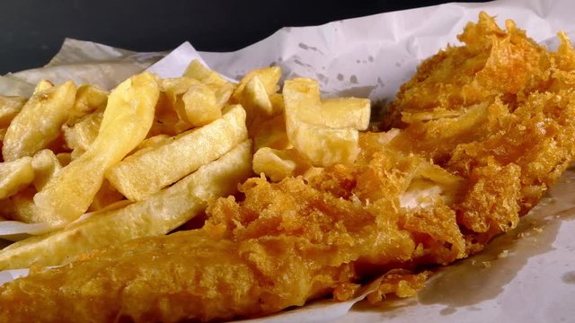 Dolly shot of a very British takeaway meal of fish and chips.