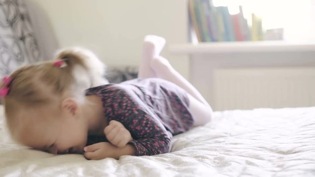Smiling little girl lying on the bed. 4K video