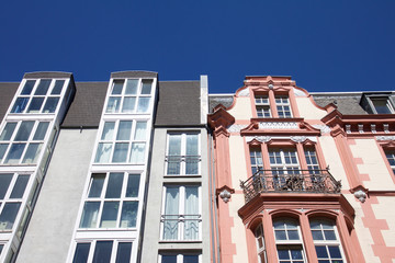 Fototapeta na wymiar Modern next to historic architecture in Aachen, Germany with townhouses with ornate carving and dormer windows in front of a blue sky