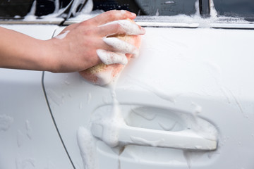 handle carwash concept - man washing car with sponge and foam