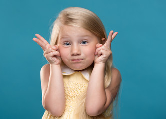 Funny, pretty, young girl showing four fingers on a blue background
