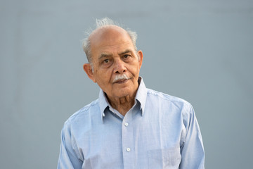 A senior Indian / South Asian man against a light blue background