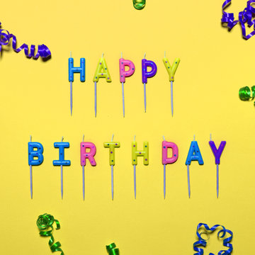 Happy Birthday flat lay party decorations on yellow background