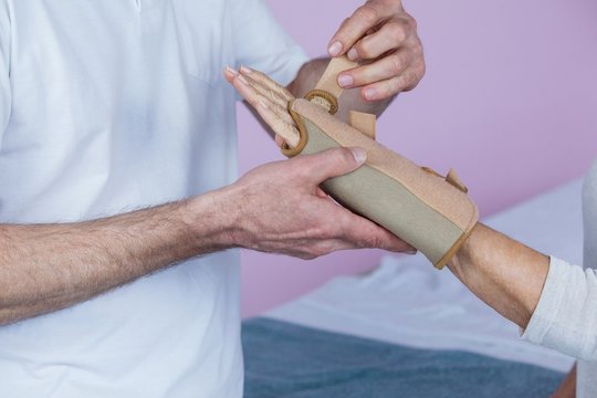 Mid section of physiotherapist examining a senior womans wrist