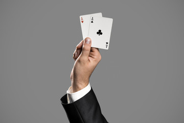 A Businessman Holding An Aces On Gray Background. Ace In The Hol