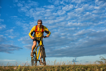 Naklejka premium Young man cycling on a rural road