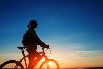 Obraz premium Silhouette of cyclist and a bike on sky background