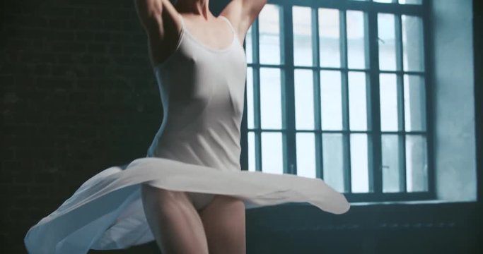beautiful ballerina in white dress performs pirouettes in the Studio, slow motion, close-up