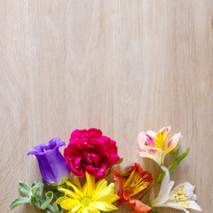 Creative arrangement made of different flowers on wooden background with space for text.