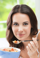 Cheerful beautiful young woman eating muslin