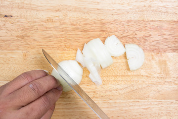 Chef slicing onion on wooden broad