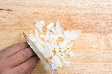 Chef slicing onion on wooden broad