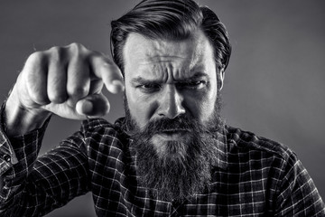 Closeup portrait of an angry bearded man threatening with his fi