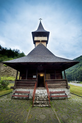 Fototapeta na wymiar Traditional wooden church in the mountains against a cloudy sky