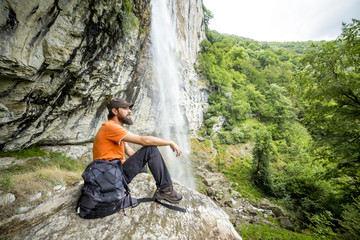 Naklejka na ściany i meble Young hiker with backpack sitting on a rock