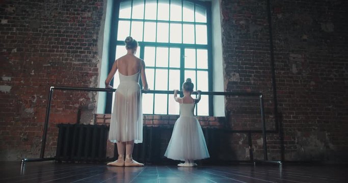 adult ballerina practicing with the little girl and trains her Russian classical ballet