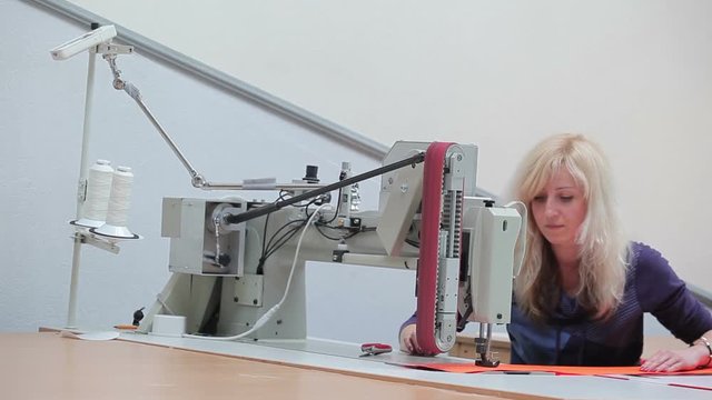 Female seamstress stitches the orange cloth