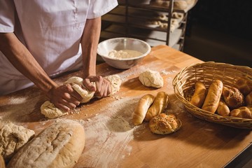 Mid-section of baker kneading a dough - obrazy, fototapety, plakaty