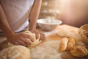 Obraz na płótnie Canvas Mid-section of baker kneading a dough