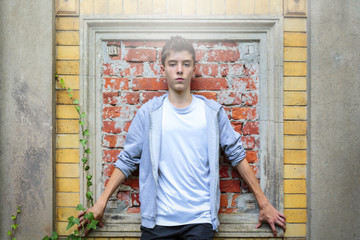 Naklejka na ściany i meble beautiful teenage boy leaning against an old wall