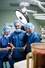 Surgeons discussing over digital tablet in operation room