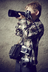 Child boy photographer with many cameras around his neck.