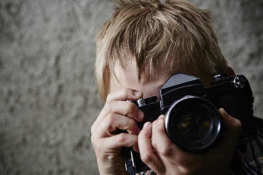 Child blond boy with vintage photo film camera photographing