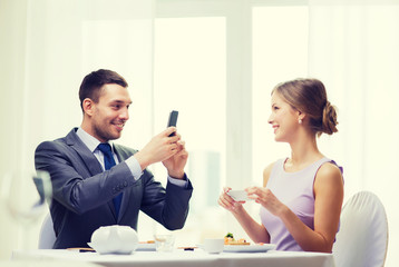 smiling couple with sushi and smartphones