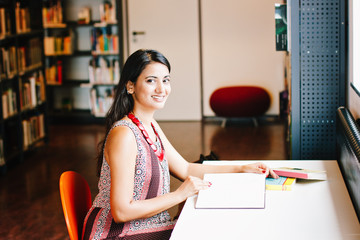 
Happy smiling indian woman studying at the library