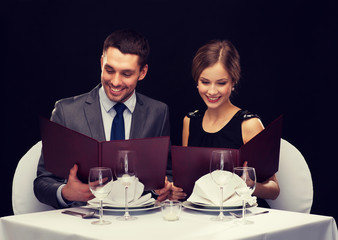 smiling couple with menus at restaurant