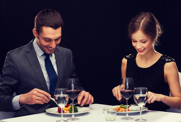 smiling couple eating main course at restaurant